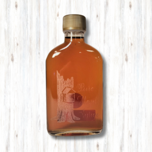 maple syrup in a glass bottle etched with a maple tree and sap bucket